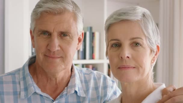 Love, library and portrait of an elderly couple standing by a bookshelf in their modern home. Care, smile and happy marriage between a senior man and woman in retirement holding each other in a house. - Materiaali, video