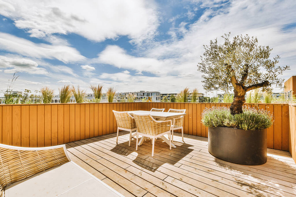 Gepflasterte Terrasse mit Sitzecke und kleinem Garten in der Nähe von Holzzaun - Foto, Bild