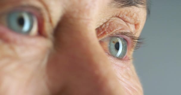 Senior woman blue eyes, lashes and wrinkle skin thinking against a studio background. Zoom in face or head of elderly woman lonely and thoughtful in retirement with light reflection in eye alone. - Materiał filmowy, wideo