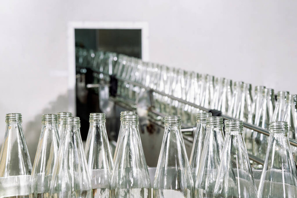 Surové skleněné láhve na aytomatickém dopravníku ve výrobní lince nápojového průmyslu v továrně - Fotografie, Obrázek