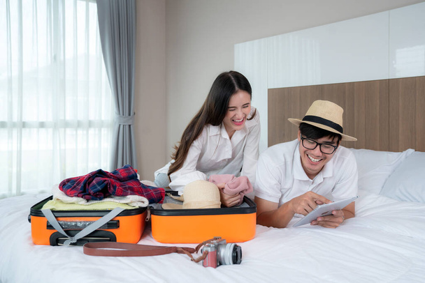 asiático pareja preparar ellos equipaje para viaje en a mañana en hotel habitación - Foto, imagen