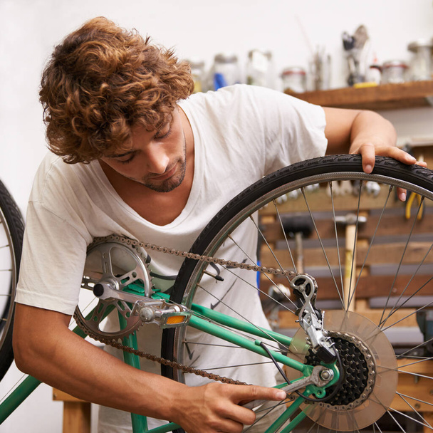 Fixing things is what I do best. a young man fixing a bicycle - Foto, imagen