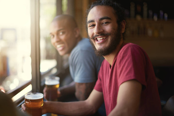 The fun is just getting started. Portrait of two friends enjoying themselves in the pub - Photo, Image