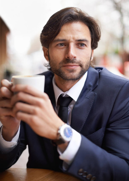 Nothing more relaxing than a good cup of coffee. A thoughtful businessman drinking coffee outdoors at a coffee shop - Photo, image