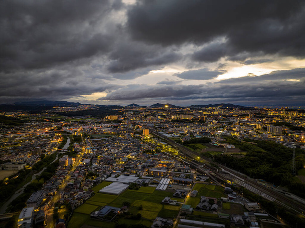 Vista aérea de las dramáticas nubes de tormenta sobre las extensas luces de la ciudad al amanecer. Foto de alta calidad - Foto, Imagen