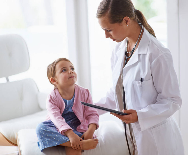 Visiting the doctor can be fun. an adorable young girl with her pediatrician - Foto, Imagen
