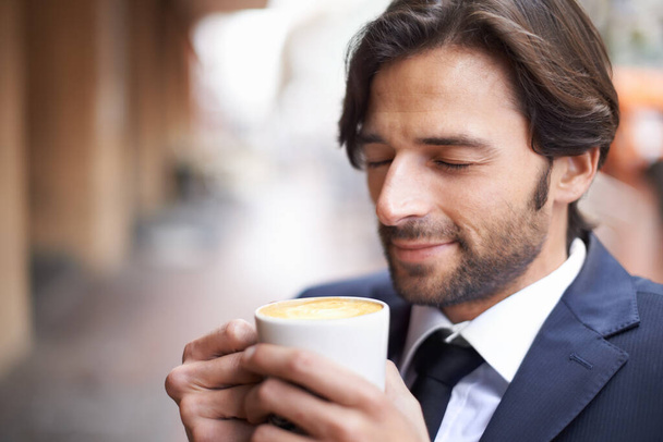 Nothing like the first sip of the day. A handsome businessman enjoying a cup of coffee outdoors at a coffee shop - Foto, imagen