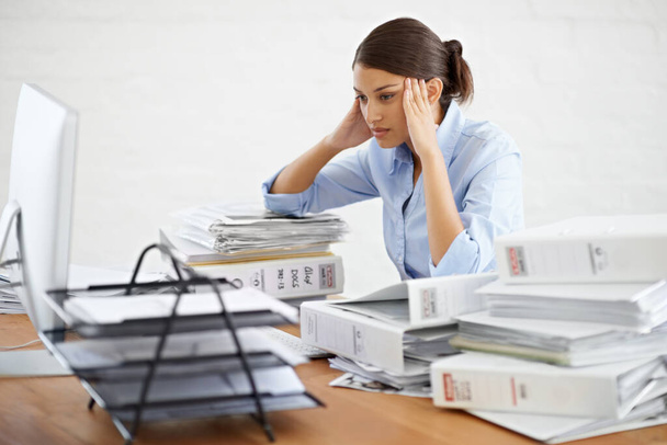 This is mind-numbing work. A young businesswoman looking overwhelmed while surrounded by paperwork - Photo, Image