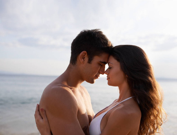 No se me ocurre mejor manera de pasar el día. Una joven pareja compartiendo un momento romántico en una playa - Foto, imagen