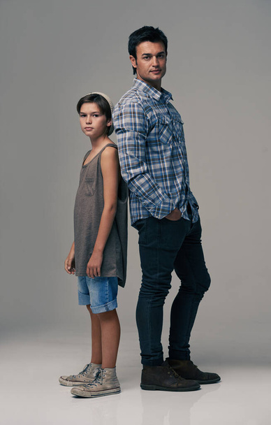 Handsome hipsters. Studio shot of a trendy father and son back to back against a gray background - Photo, Image