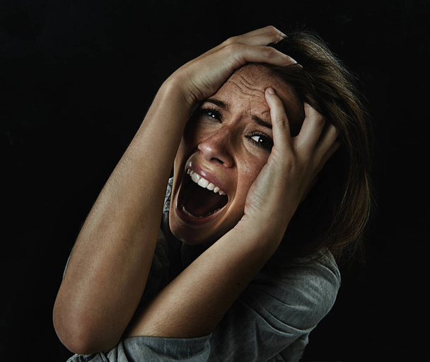 Por favor... ajuda-me. Uma jovem mulher gritando incontrolavelmente enquanto isolada em um fundo preto - Foto, Imagem