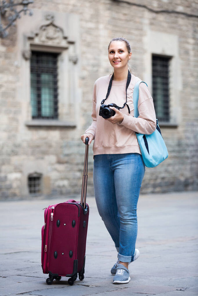 Smiling girl is walking around the city with camera. - Valokuva, kuva