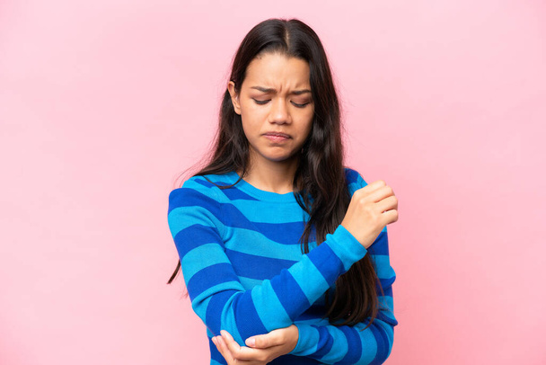 Young Colombian woman isolated on pink background with pain in elbow - Fotografie, Obrázek