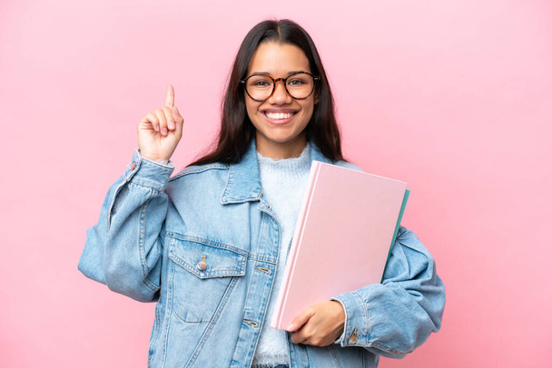 Νεαρή φοιτήτρια Κολομβιανή απομονωμένη σε ροζ φόντο δείχνοντας μια σπουδαία ιδέα - Φωτογραφία, εικόνα