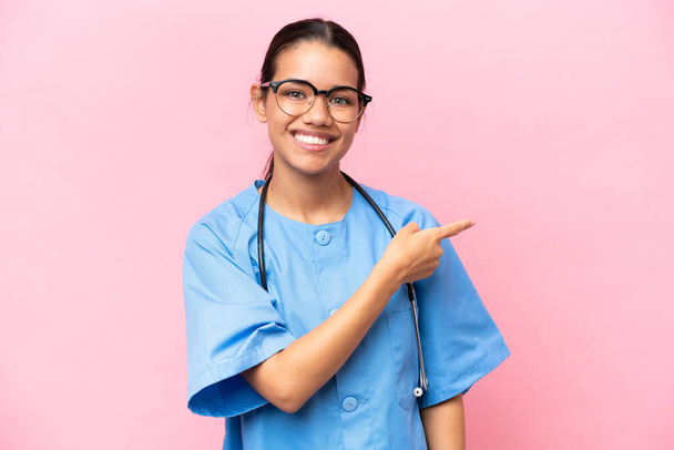 Young nurse Colombian woman isolated on pink background pointing finger to the side - Foto, Imagen