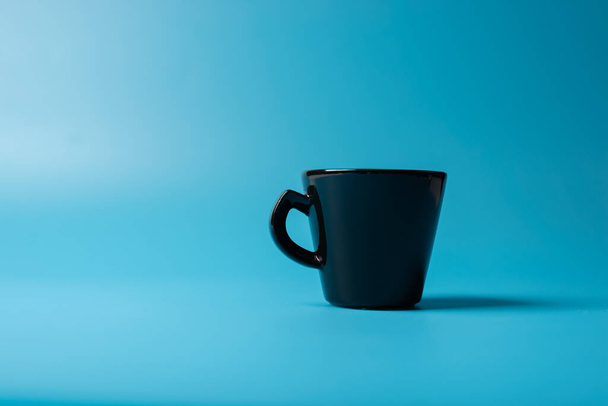 A black cup a blue background. Minimalism - Φωτογραφία, εικόνα