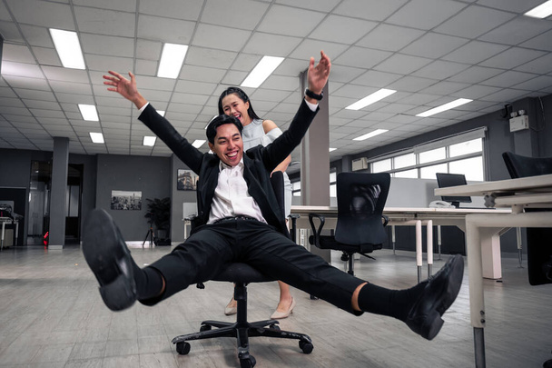 Businessman having fun and push office chair taking a break in the office at work - Photo, Image