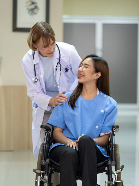 Médico conversa com paciente sentado em cadeira de rodas no hospital. - Foto, Imagem