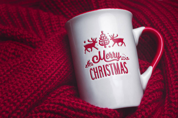 Натюрморт с рождественской кружкой на тёплом и красном свитере. Счастливой рождественской кружки на уютном красном свитере. Рождество и зима. - Фото, изображение