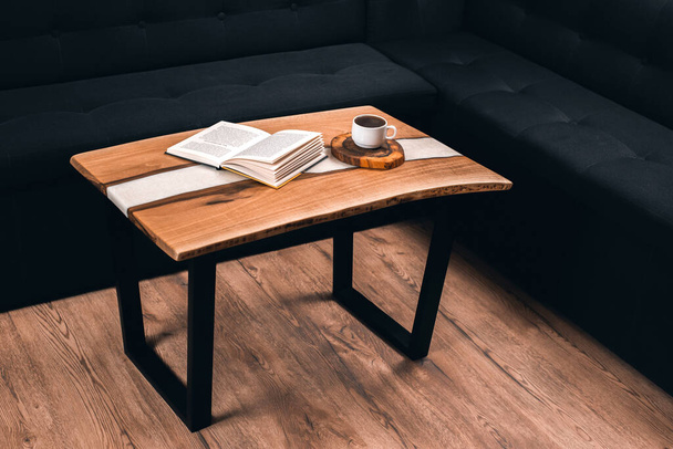 Epoxy houten tafel. Een kop koffie en een boek op tafel. Ochtend en ontbijt - Foto, afbeelding