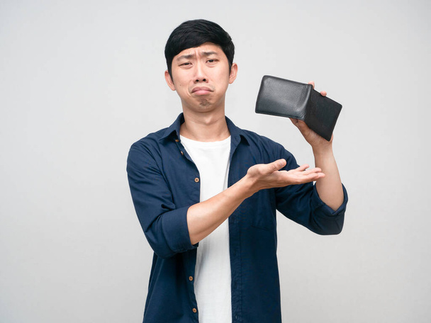 Unzufriedener asiatischer Mann schüttelt Geldbörse, um Geld zu finden - Foto, Bild
