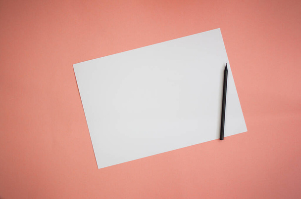 Weiße Karte und schwarzer Bleistift auf rosa Hintergrund. Vorlage. - Foto, Bild