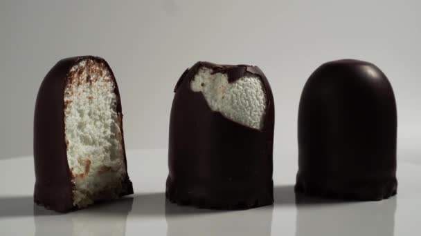 Marshmallow traktaties in chocolade op een witte achtergrond. - Video