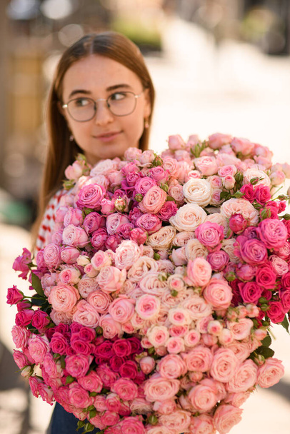 Close-up of beautiful lush bouquet of fresh roses of different pink colours which woman holds - 写真・画像