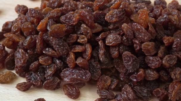 Gros plan de raisins secs isolés sur un fond en bois. Aliments secs - Séquence, vidéo