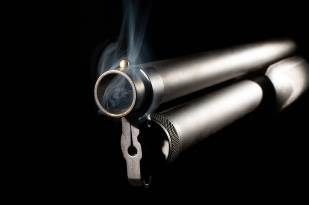 Gun barrel still smoking after a shot on a black background - Fotó, kép
