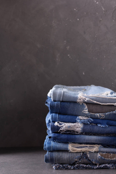 Arka planda mavi kot pantolon yığını. Kot kumaş yığını malzeme yüzeyi olarak - Fotoğraf, Görsel