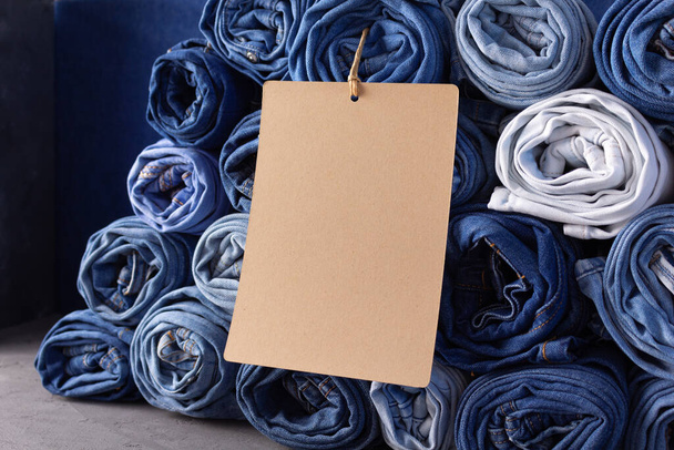 Paper price tag label at jeans background texture. Blue jeans denim fabric - Φωτογραφία, εικόνα