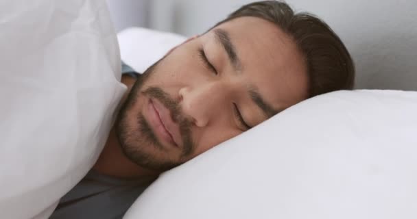 幸せな男がベッドで目を覚ますと自宅で午前中に笑顔。朝の若い男性の顔は、休暇や平和的な睡眠の残りの部分でリラックス。愛挨拶人,怠惰な疲れた日とベッドルーム枕のポルノの. - 映像、動画