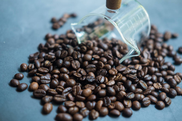 Scattered coffee beans from a transparent glass. Close up - Φωτογραφία, εικόνα