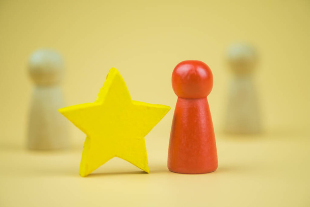 競争相手と黄色の星とは異なると目立つ木製の赤い人形。リーダーの概念。組織内の個人のレベルを上げるという概念 - 写真・画像