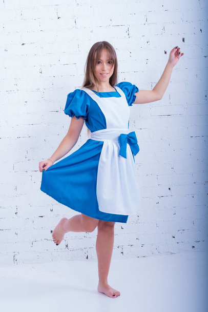 beautiful young woman dressed as alice in wonderland, distracted from the photo camera, - Foto, Bild