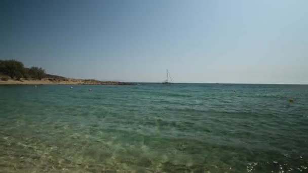 Pohled na krásnou tyrkysovou pláž Magganari a plachetnici v dálce v Ios Greece - Záběry, video
