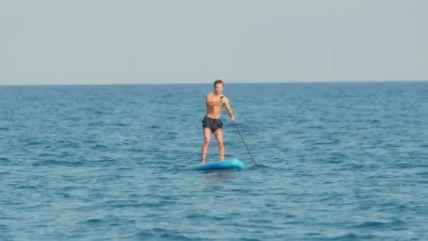 Boy walks with sup board on calm sea in Autumn near the island. - Footage, Video