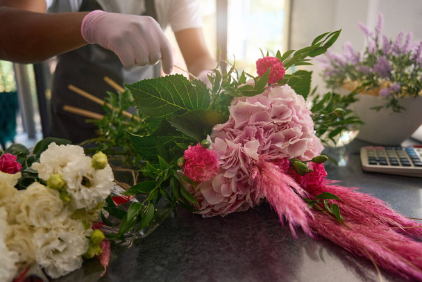 Hands wrapping a bouquet of flowers lying on the table - 写真・画像
