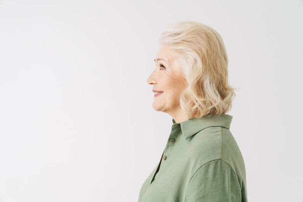 Grey senior woman in shirt smiling while looking in profile isolated over white background - Φωτογραφία, εικόνα
