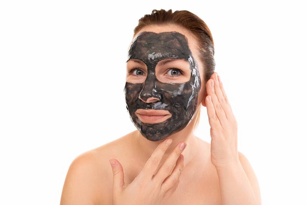 γυναίκα με μαύρη καλλυντική μάσκα στο πρόσωπό της. - Φωτογραφία, εικόνα