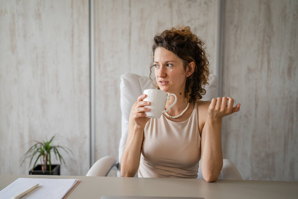 Una giovane donna caucasica che beve caffè in ufficio durante la pausa business woman modern entrepreneur concept - Foto, immagini