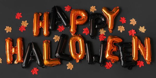 Tekst HAPPY HALLOWEEN gemaakt van ballonnen en herfstbladeren op donkere ondergrond - Foto, afbeelding