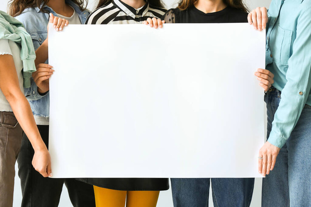 Vrouwen met blanco vel papier op witte achtergrond, close-up - Foto, afbeelding