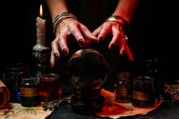 Witch with crystal ball reading future on dark background - Photo, Image