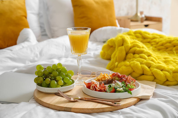 Wooden tray with tasty breakfast on bed - Φωτογραφία, εικόνα