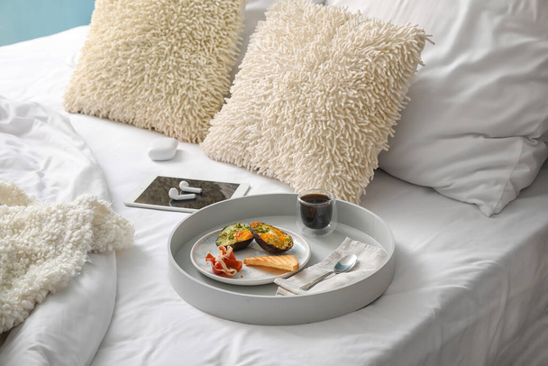 Tablett mit leckerem Frühstück und Tasse Kaffee auf dem Bett - Foto, Bild