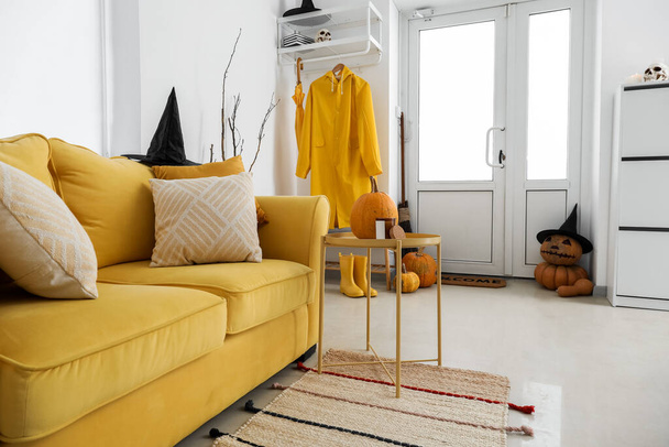 黄色のソファとレインコートでハロウィンのために飾られたホールのインテリア - 写真・画像