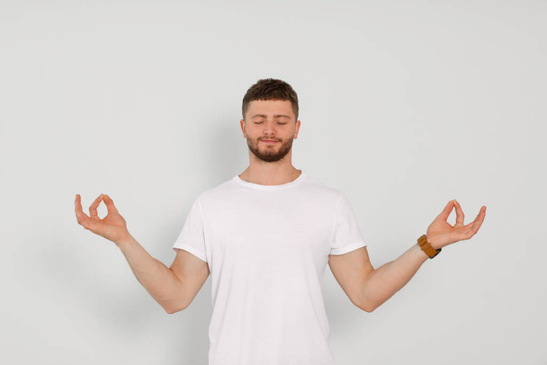 Young man meditating on white background. Zen concept - 写真・画像