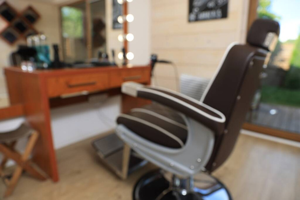 Blurred view of stylish hairdresser's workplace with professional armchair in barbershop - Foto, afbeelding